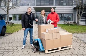 Andreas Richter (links) und Melanie Steinhilber (Mitte) von Uhlsport übergeben Sportausrüstung für die Erdbebenopfer in die Türkei an Andreas Will vom SSV Reutlingen (rechts)